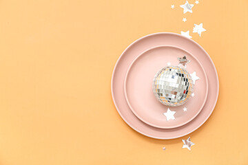 Beautiful table setting with confetti and Christmas ball on orange background