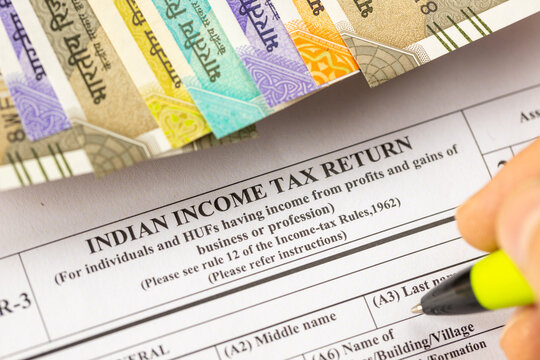  taxes. A man filling out an Indian income tax form, placed on a desk with a calculator and rupees. Selective focus. Financial concept