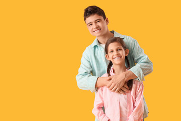 Fototapeta premium Smiling brother and sister on yellow background