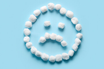 Sad face made of cotton on blue background