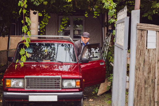A senior Caucasian male driver is preparing to get into an old-fashioned car.