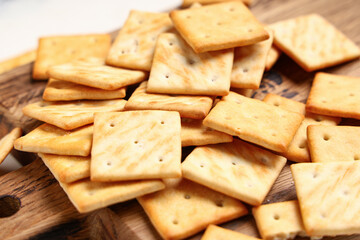 Wooden board with tasty crackers on white background, closeup