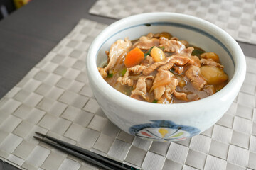 箸を添えた木目テーブルの上の肉うどん