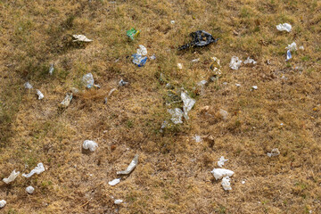 Litter polluting dry grass, showing environmental damage