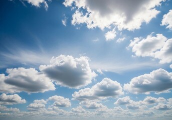A high-resolution photograph of a bright blue sky filled with soft, fluffy cumulus clouds. The clouds appear voluminous and scattered across the horizon, illuminated by natural sunlight. Captured from