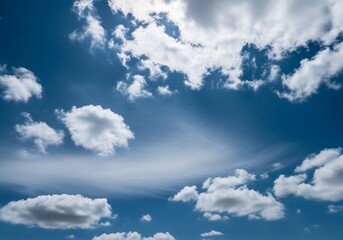 A high-resolution photograph of a bright blue sky filled with soft, fluffy cumulus clouds. The clouds appear voluminous and scattered across the horizon, illuminated by natural sunlight. Captured from