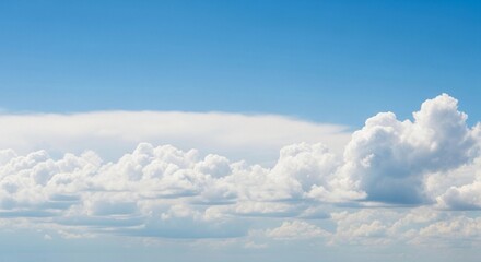 A high-resolution photograph of a bright blue sky filled with soft, fluffy cumulus clouds. The clouds appear voluminous and scattered across the horizon, illuminated by natural sunlight. Captured from