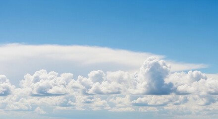 A high-resolution photograph of a bright blue sky filled with soft, fluffy cumulus clouds. The clouds appear voluminous and scattered across the horizon, illuminated by natural sunlight. Captured from