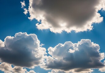A high-resolution photograph of a bright blue sky filled with soft, fluffy cumulus clouds. The clouds appear voluminous and scattered across the horizon, illuminated by natural sunlight. Captured from