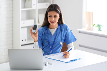 Female doctor with glucometer giving online consultation in clinic
