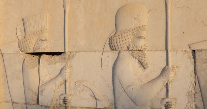 Close view of an Achaemenid stone relief at Persepolis: Persian guards in profile holding spears, curling beards and rosette motifs. Warm side light reveals ancient craftsmanship, ceremony, and empire