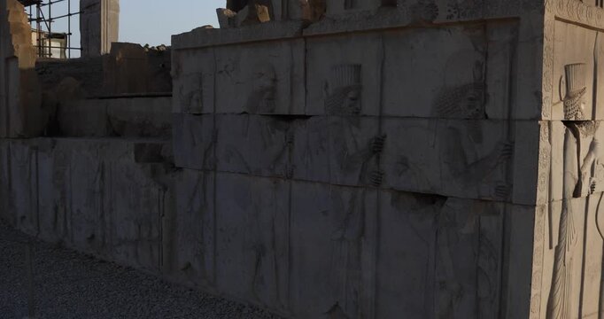 Oblique view of a Persepolis relief wall at the corner, rows of Persian guards receding in perspective. Warm low sun reveals chisel marks, ceremony, and enduring Achaemenid heritage.