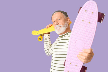 Senior man with skateboard on lilac background
