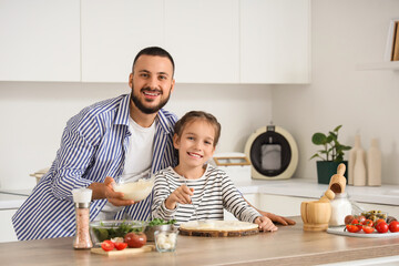 Father with his daughter spreading sauce on pizza dough in kitchen