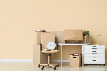 Workplace with cardboard boxes near beige wall in office on moving day