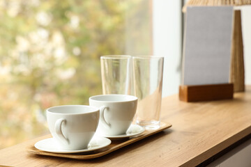 Tray with cups of tea on wooden table in stylish hotel room, closeup
