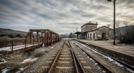 Obraz premium Forgotten railway: Rusty bridge and abandoned station under cloudy skies