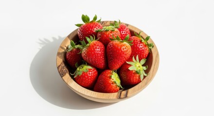 Bowl of fresh ripe strawberries on a white surface bathed in sunlight