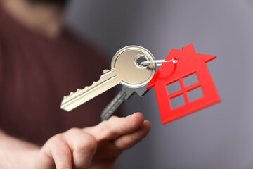 Close-up shot of a hand holding keys with a house-shaped tag. Symbolizes home ownership, investment, and new beginnings in real estate. Perfect