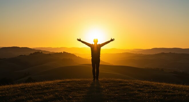 Silhouette of a Person with Open Arms Celebrating Sunrise Over Rolling Hills and Distant Mountain