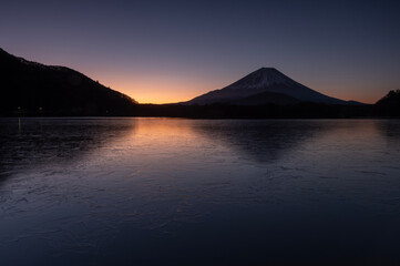 冬の精進湖の湖面に浮かぶ氷紋と夜明けの富士山