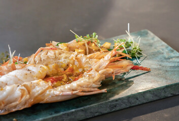 Close up to the Lobster Pad Thai is ready to serve with fried noodle, tofu and other ingredients on a rectangular plate in studio light.