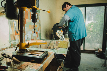 Latino man working in his workshop. Knife maker.