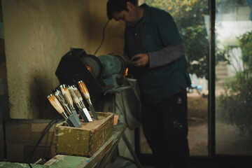 Latino man working in his workshop. Knife maker.