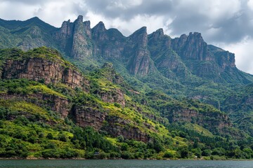 Fototapeta premium Rugged Mountain Range Overlooking Serene Lake Under Cloudy Sky