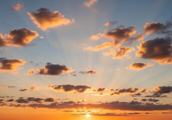 A peaceful evening sky with scattered cumulus clouds glowing in warm orange, pink, and light blue hues. The sun sets below the horizon, casting soft light rays upward. Captured in full HD from a groun