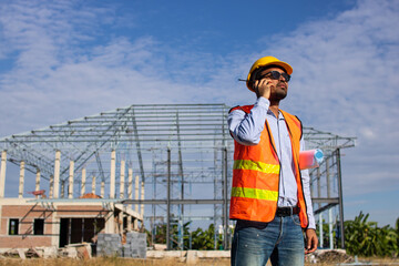 Male Construction worker or Engineer or Foreman stands at a building site using a walkie-talkie...
