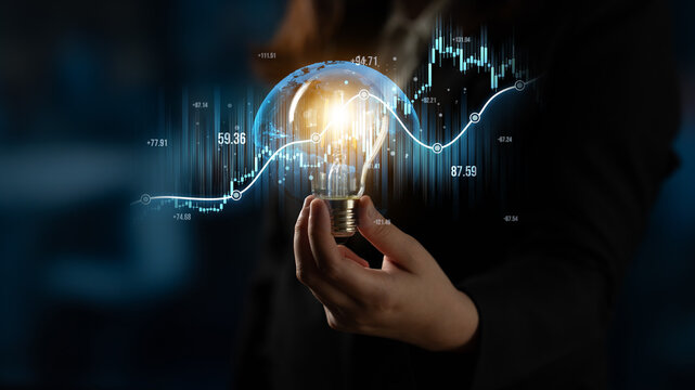 A business professional holds a light bulb symbolizing innovative ideas against a backdrop of financial graphs, representing data analysis and future strategies. Scalp - Powered by Adobe