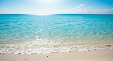 Obraz premium Beautiful turquoise ocean waves gently washing onto the sandy beach under the bright sun.