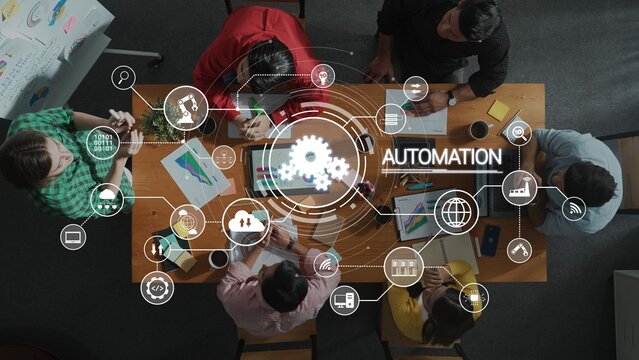 A diverse group of professionals collaborates in a modern office setting, surrounded by graphics of automation, exploring innovative ideas and strategies. Raster - Powered by Adobe