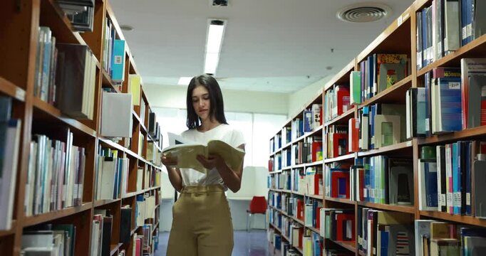 Asian woman reading book in a library for education, studying and research in school, university or college campus. Focus, book and student at bookshelf for language learning or philosophy knowledge 