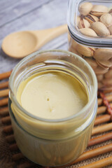 Creamy pistachio spread in glass jar on wooden table