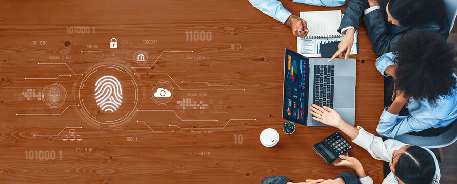 A group of professionals engages in a collaborative meeting focused on digital security, utilizing a laptop, documents, and various analytical tools on a wooden table. Trope