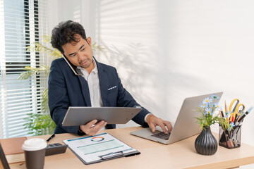 Naklejka premium A confident businessman calculating budget and reviewing company performance using reports and charts in a clean modern office, focusing on financial goals, investments, and strategic success.