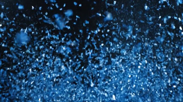 Burst of shiny blue confetti on a black background