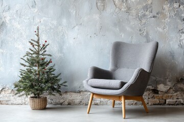 Minimalist gray armchair and small decorated Christmas tree by distressed wall.