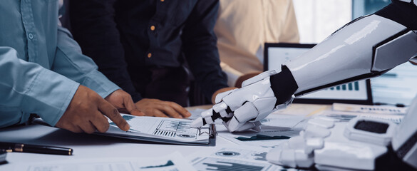 A modern office scene shows a robot arm assisting humans in data analysis, emphasizing teamwork and the integration of technology in professional environments.Noogenesis