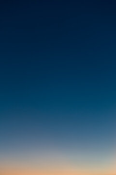 Vertical photo of a beautiful clear evening sky without clouds. Sky gradient from orange to dark blue.