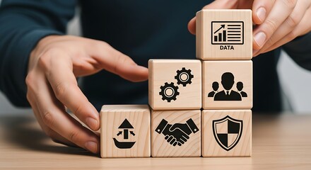 Hands stacking wooden blocks with business symbols representing growth and partnership in a modern office setting, conveying a sense of collaboration and success.