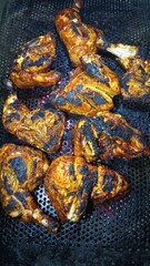 Spicy grilled chicken pieces on barbecue grill.