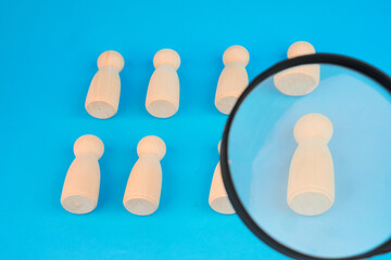 Magnifying glass examining one figure in a group, illustrating candidate screening and a focused talent search.
