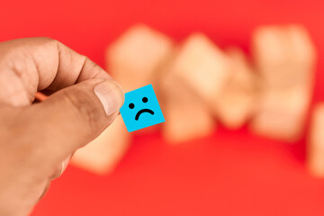 Hand holding a sad face note to portray Blue Monday and the idea of low mood at the start of the week while inviting support and motivation.
