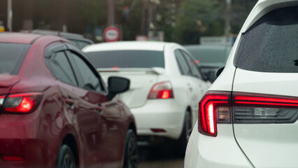 Rear side of white car with turn on brake light. Traffic jam on the road after rainy time. on the body of car with drop of water rain. Blurred traffic jam in the city with trees.