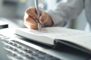 Closeup, woman writing on calendar event planner to set timetable organize schedule, event planning...