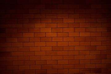 A brick wall with a dark brown color. The wall is made of bricks and has a rough texture
