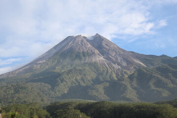 Fototapeta premium Majestic view of a conical volcano rising above lush forested slopes, with its summit transitioning from green vegetation to exposed rock and ash